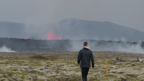 a man runs up to get a distant view of the erupting grindavik volcano in sundhnúkur crater, iceland