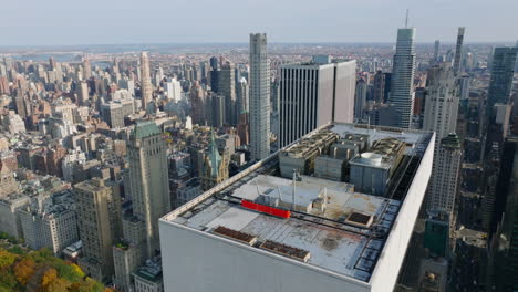 Rückwärts-Fliegen-über-Der-Spitze-Des-Wolkenkratzers-Mit-Rotierenden-Ventilatoren-Von-Klimaanlagen.-Kippen-Sie-Die-Enthüllung-Des-Stadtbildes-Nach-Oben.-Manhattan,-New-York-City,-Vereinigte-Staaten