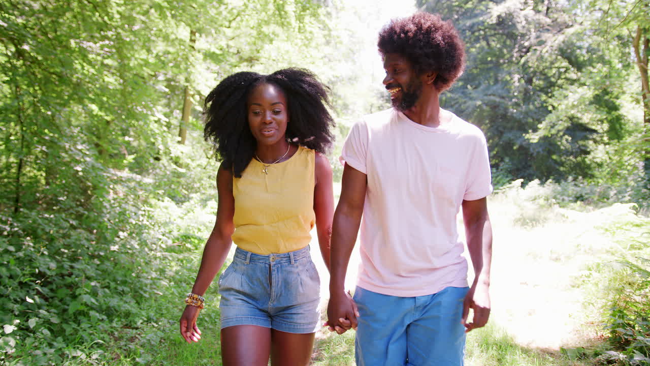 A black couple holding hands during a walk in a forest