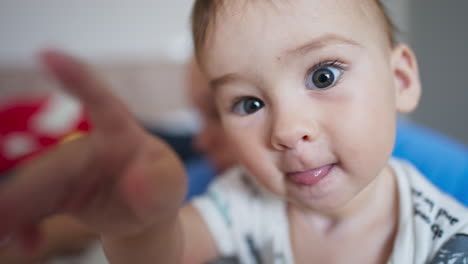 healthy caucasian kid looking into camera. adorable boy touching camera with curiosity. close up. blurred backdrop.