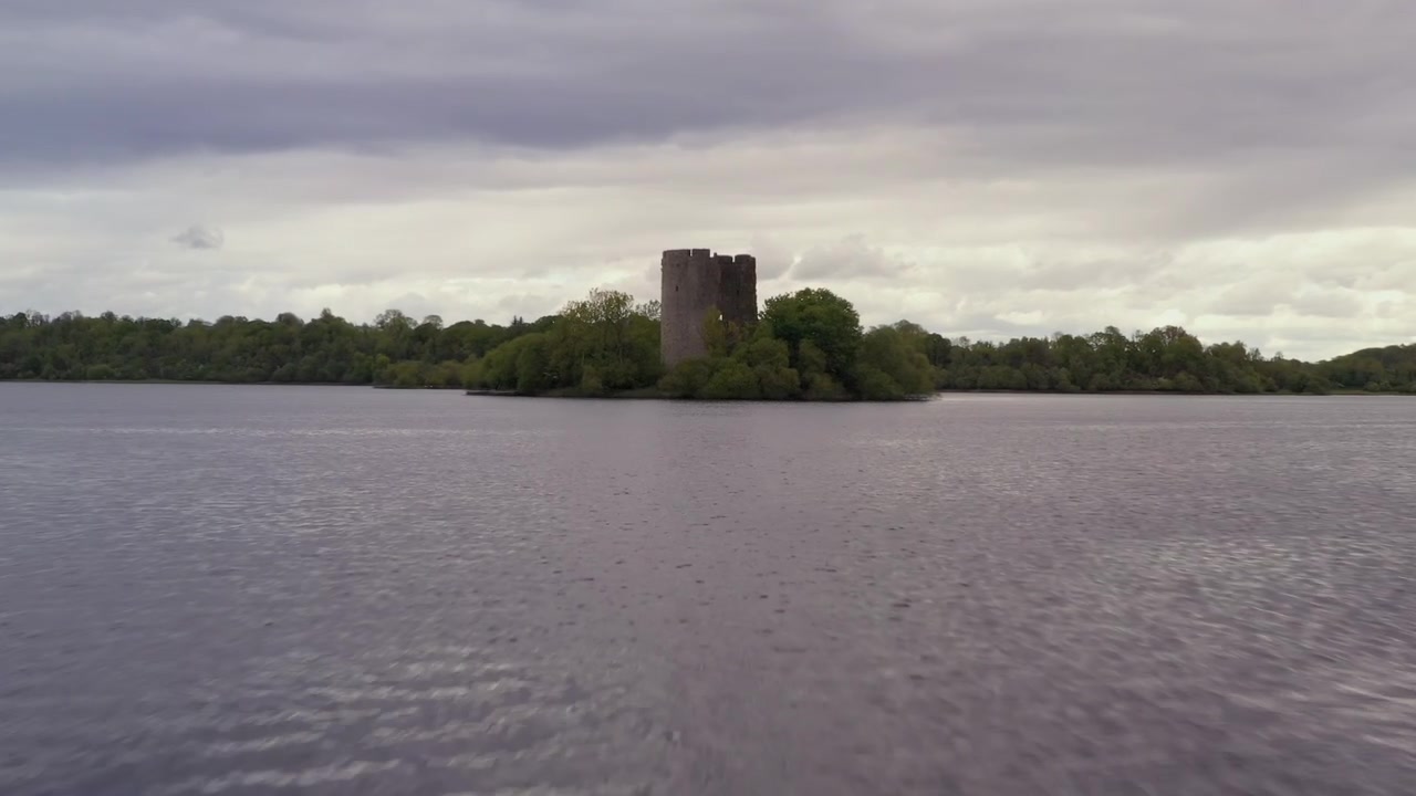 Hurtig luftbåren dolly-optagelse, der skimmer hen over vandet og suser mod den centralt placerede Cloughoughter Castle-ø, med slående bevægelse i forgrunden og fængslende komposition.