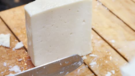 cutting a block of feta cheese on a cutting board