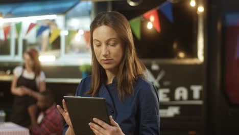 Schöne-Frau-Mittleren-Alters-Mit-Tablet-Gerät-Im-Freien-Food-Truck-Bar-Auf-Der-Messe