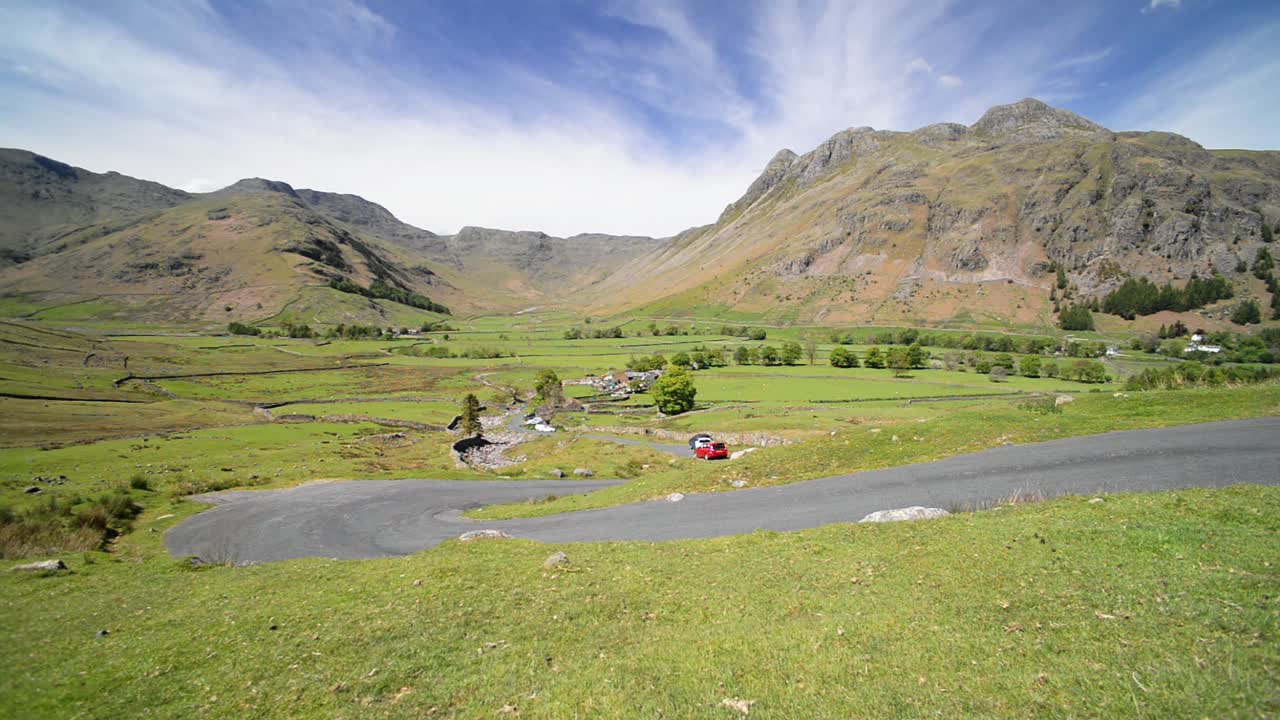 Cars traveling down the winding road in the beautiful England Lake District - wide shot