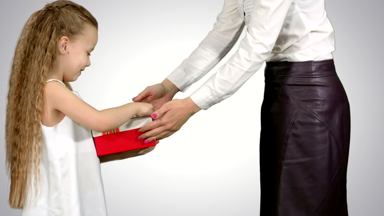 una joven madre encantadora y su linda hija abrieron regalos de navidad sobre un fondo blanco.