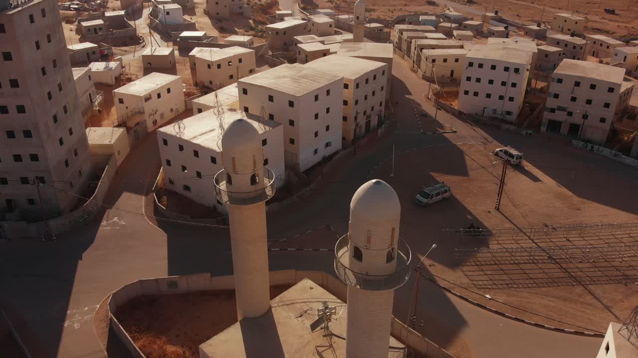 aerial shot of two mosques next to the main squere in an old empty city in the desert in palestine near Gaza at sunset.