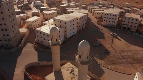 aerial shot of two mosques next to the main squere in an old empty city in the desert in palestine near gaza at sunset.