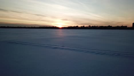 Lago-Congelado-Al-Atardecer,-Cámara-Avanzando-Sobre-La-Nieve