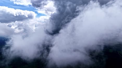 a stunning, immersive aerial drone shot flies close to and through majestic white and grey clouds, revealing the vast green forest landscape of latvia below