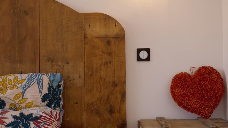 Slow descending shot of a funky bed cover with a red heart on the bedside table