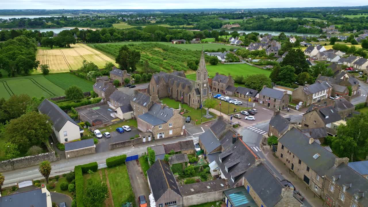 Picturesque village of Saint-Cast-le-Guildo castle in Brittany, historic church, lush green French countryside, France. Aerial drone forward