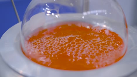 laboratory round bottom flask heating equipment - boiling orange liquid: closeup