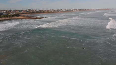 Sobrevuelo-Cinematográfico-De-Surfistas-Y-Olas-Rodando-Hacia-La-Playa-De-Middleton,-Australia-Del-Sur