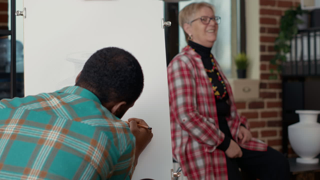 African american man holding pencil to sketch vase model