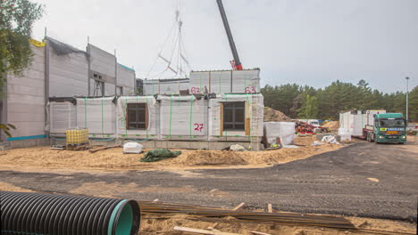 Timelapse-shot-of-crane-lifting-up-and-placing-the-white-container-shaped-rooms-from-day-to-night-time