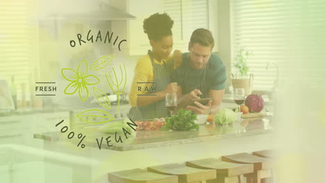 animation of organic vegan text over diverse couple preparing healthy meal in kitchen