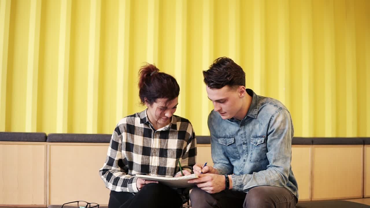 dos jóvenes atractivos disfrutan de su tiempo juntos, dibujando en un bloc de notas. objetivos de pareja. relación romántica.