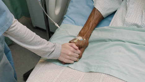 top view nurse touching hand of old man in hospital bed showing affection for elderly patient recovering from illness