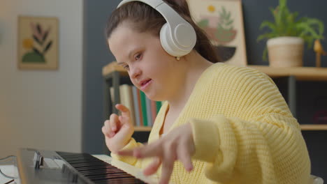 Girl with Down Syndrome in Headphones Playing Synth at Home