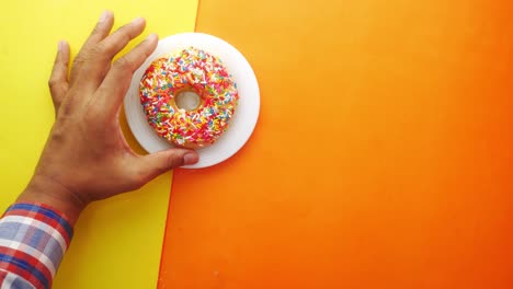 mano con una rosquilla salpicada de colores