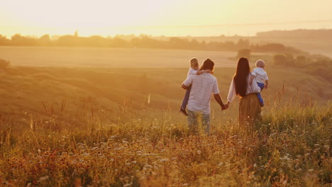 una giovane coppia divertente con due giovani figli che scortano il sole in partenza oltre i soli dell'orizzonte dell'orizzonte