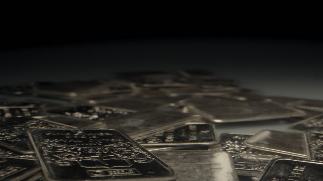 Cinematic macro dolly out of lots of silver bars in a dark vault with a large spot light lighting the precious metal