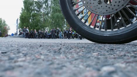 ground level shot by front wheel, motorcyclists meet for bike rally