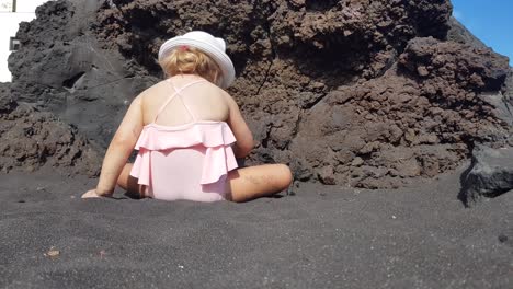 toddler girl playing on black sand beach