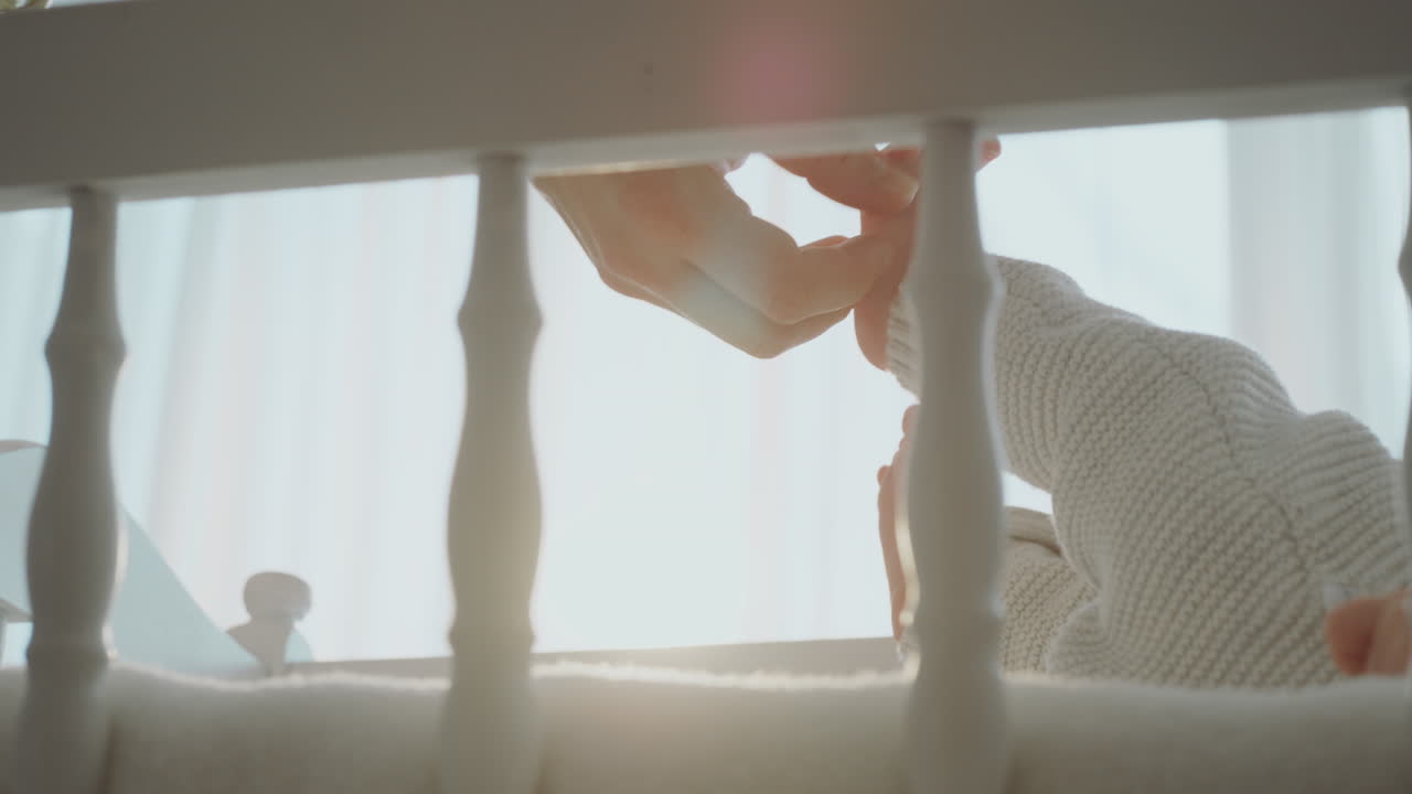 Mother touching her baby's foot in crib