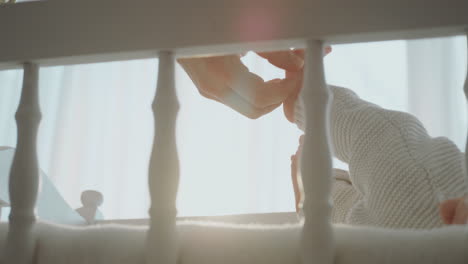 mother touching her baby's foot in crib