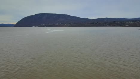 aerial footage of a wide river valley with distant mountains covered in a dusting of snow during winter