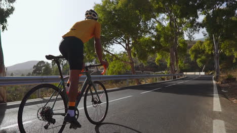 with the backdrop of a calm morning, a man cycles on his road bike on an empty road as part of outdoor exercise. the slow-motion capture accentuates the extreme sports vibe