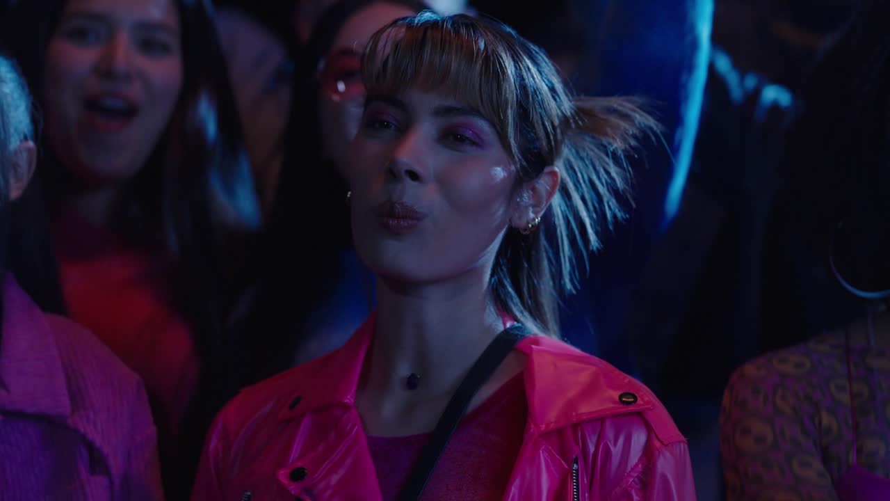 A beautiful girl watches a music concert at night with her friends while chewing gum