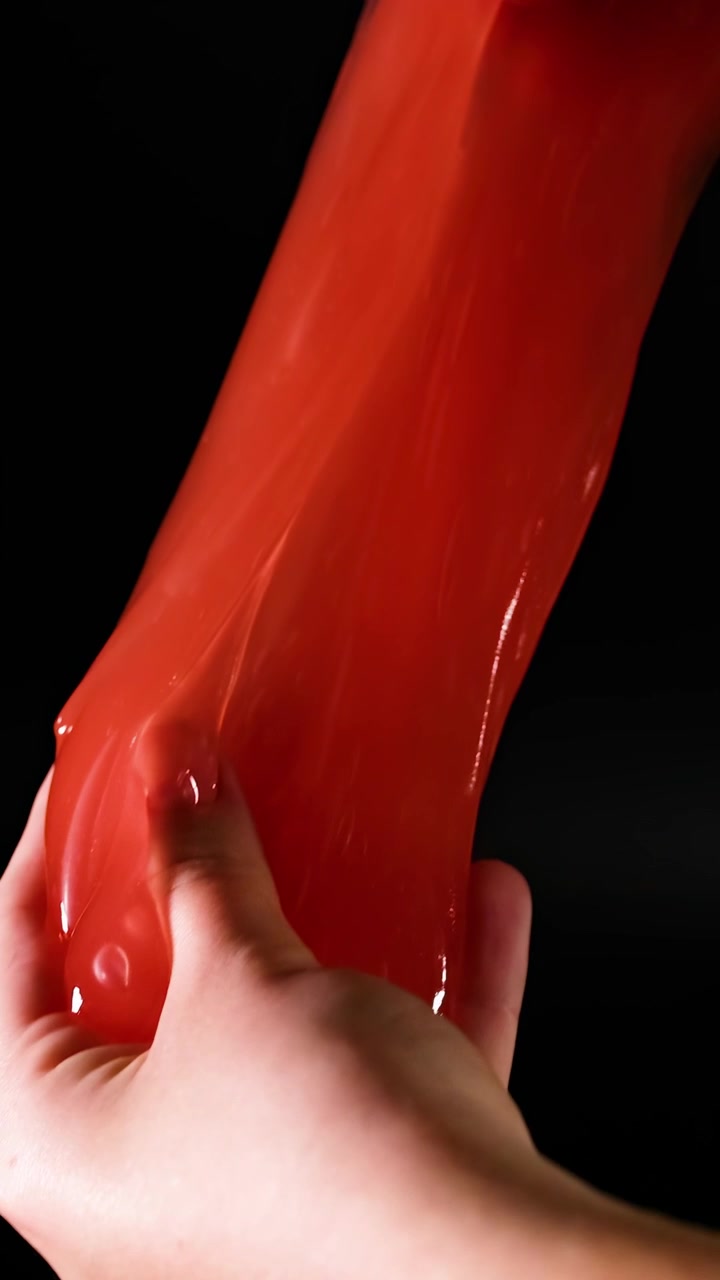 Mani che manipolano melma rossa elastica