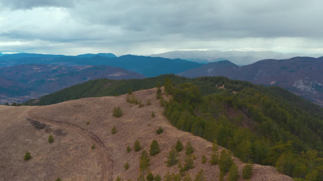 Mountain Tracks With Dense Forest Hills In Background Against Cloudy Sky. - Aerial Drone Shot