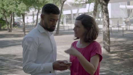 mujer madura hablando con un hombre afroamericano con un teléfono inteligente.