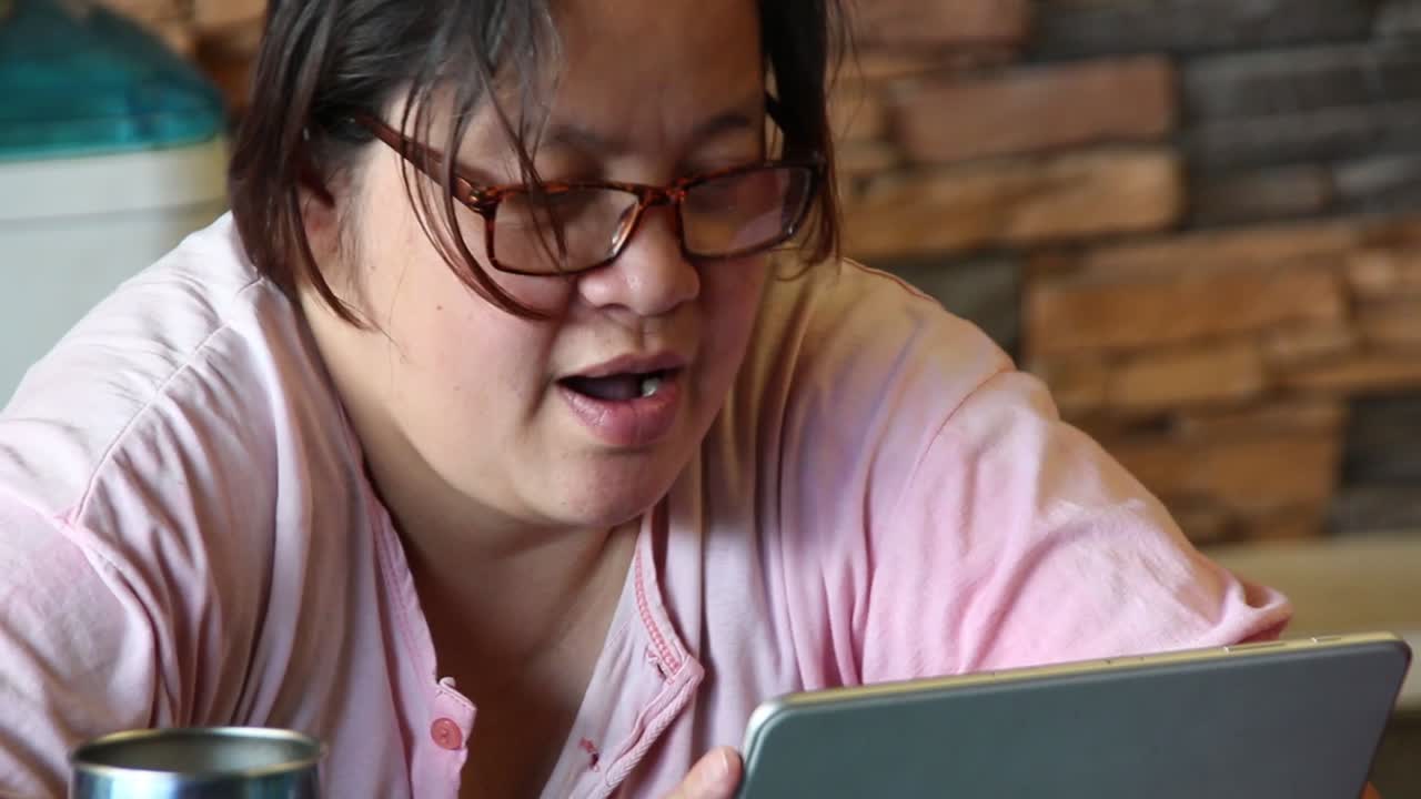 성인 여성은 태블릿을 보면서 노래를 부르며 매우 행복하고 즐거워 보입니다.