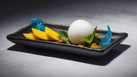 artistic dessert with mango, sorbet, and blue sugar crystals