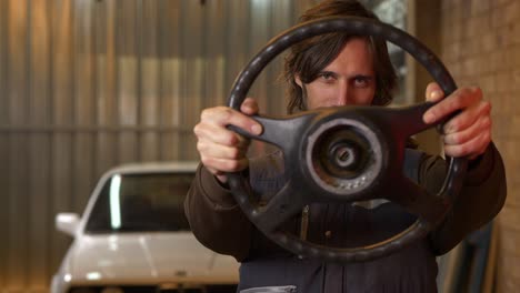 car mechanic lifts up steering wheel and stares through, slow motion closeup