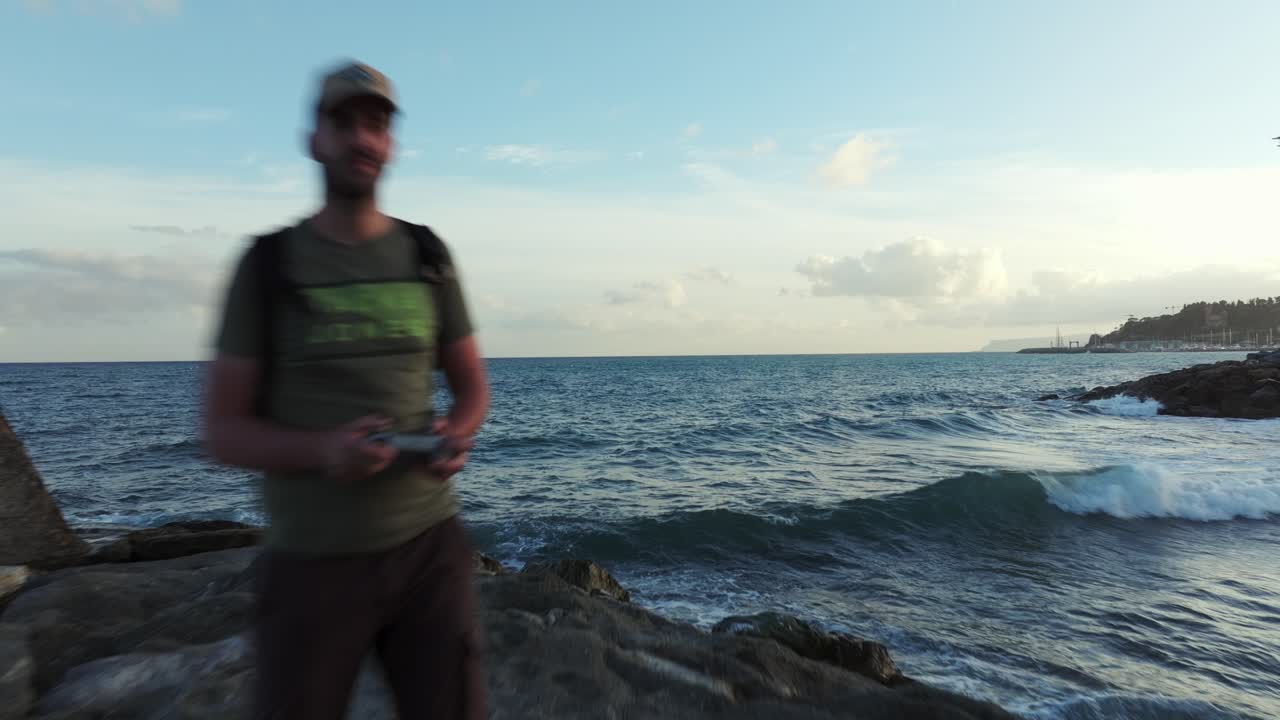drone vuela hacia el piloto de pie en el rompeolas en varazze en italia