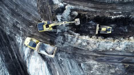 an excavator fills a dump truck with dirt at a construction site