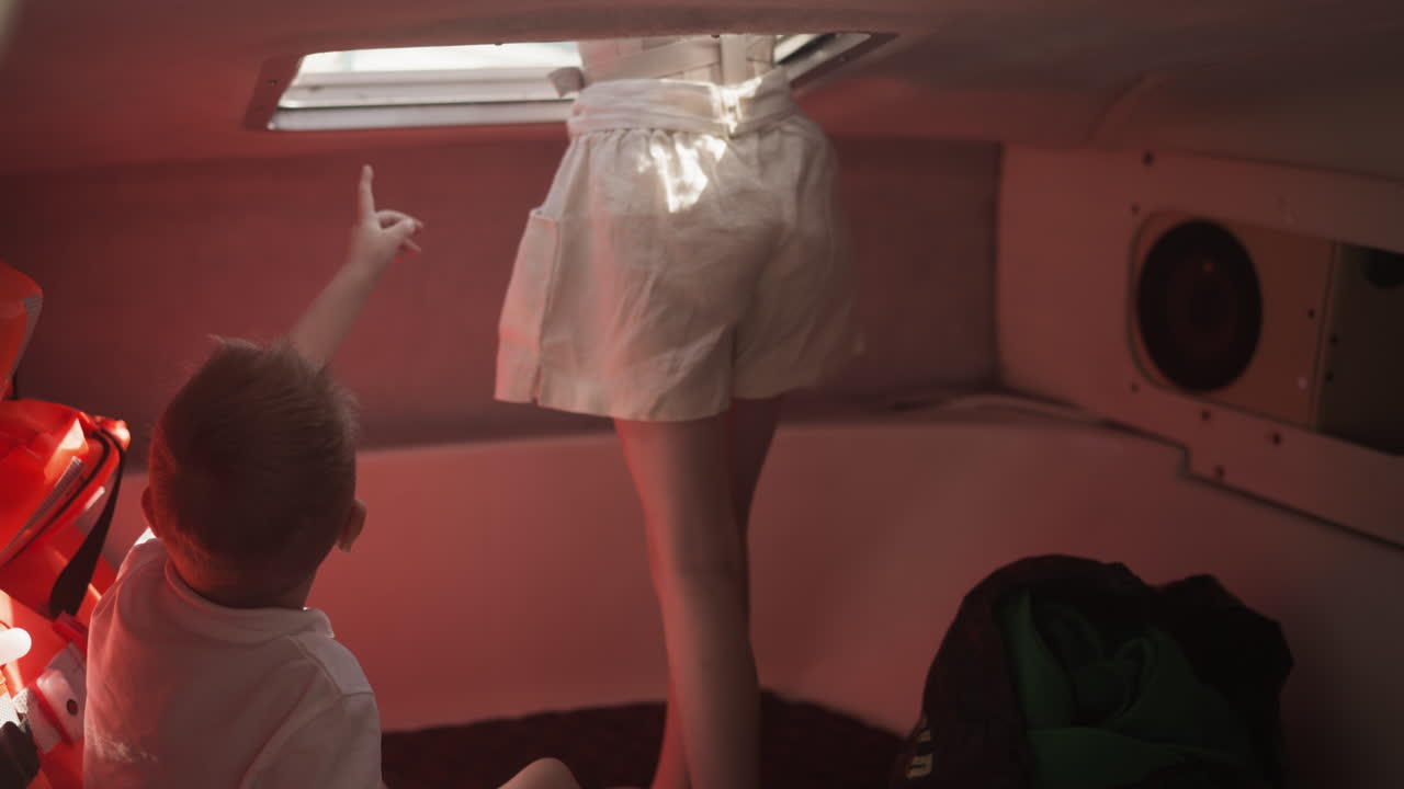 niño pequeño apunta hacia adelante y la hermana mayor mira fuera de la cabina salir montando en bote a motor juntos. los niños pasan tiempo en un yate moderno en vacaciones en el mar