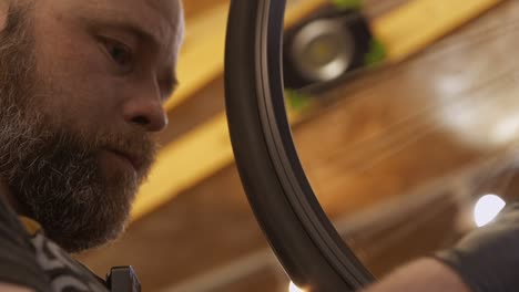 Close-up-of-male-bike-mechanic-straightening-a-wheel-in-a-workshop