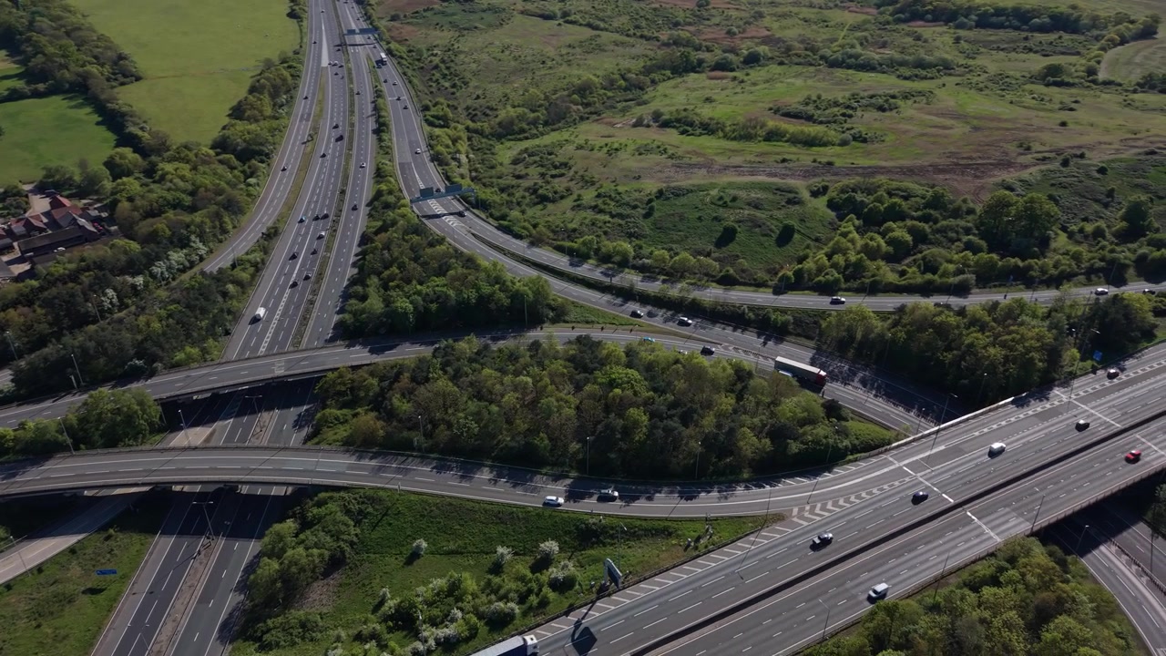 Flusso di traffico su svincolo autostradale attraverso un paesaggio rurale verdeggiante.