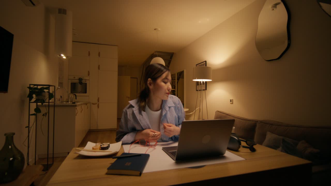 Woman working from home at night with sushi