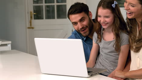 familia usando computadora portátil en la cocina