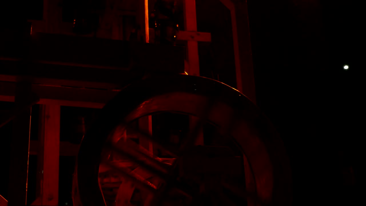 vista mágica de una antigua muestra de molino de agua con una gran rueda movida por una corriente de agua y una cadena metálica con algunos palos en el fondo negro