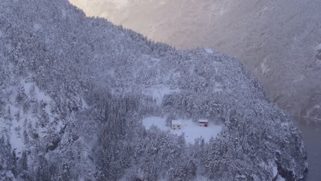 Top-down-view-Small-isolated-farm-surrounded-by-snowy-woods-Glow-lights,-Snowfall-Landscape