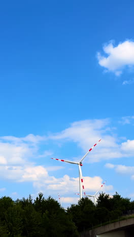 wind turbines under a bright blue sky. wind turbines spin gracefully on a sunny day, surrounded by greenery and a clear blue sky