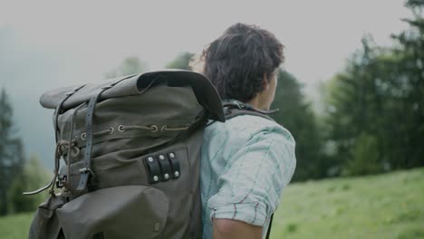 handheld tracking shot of backpacker millennial man hiking on temperate forest trail